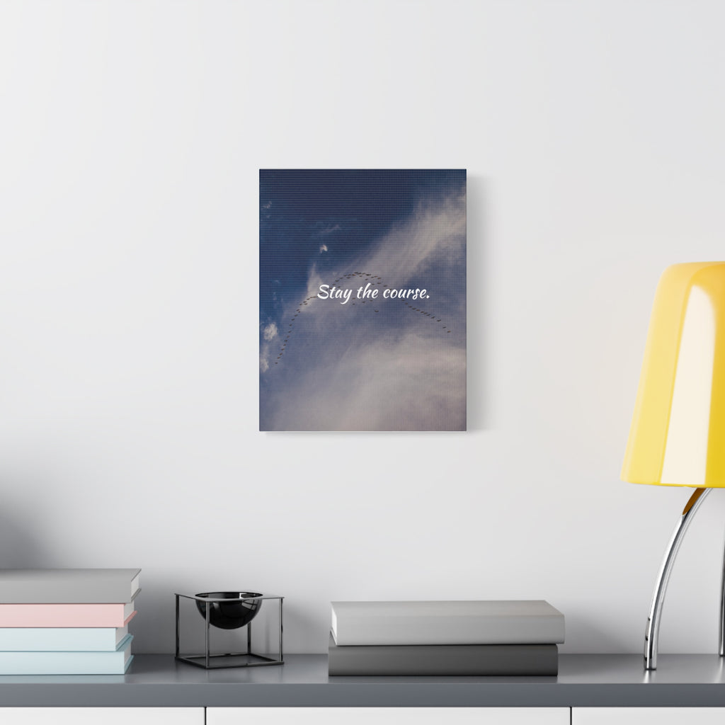 Wall art with 'Stay the course.' text on a shelf with books and a lamp.
