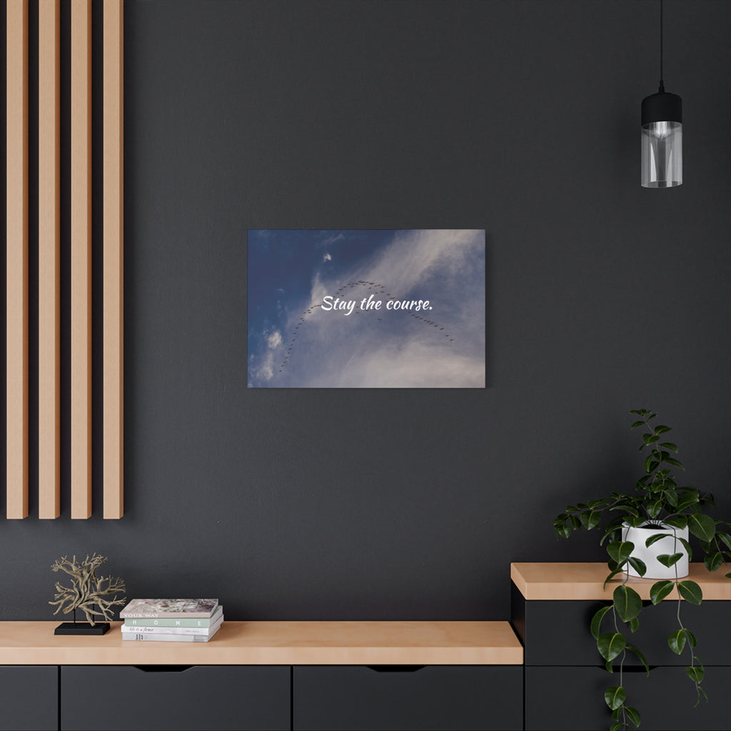 Canvas print with 'Stay the course.' text on a dark wall above a wooden shelf.