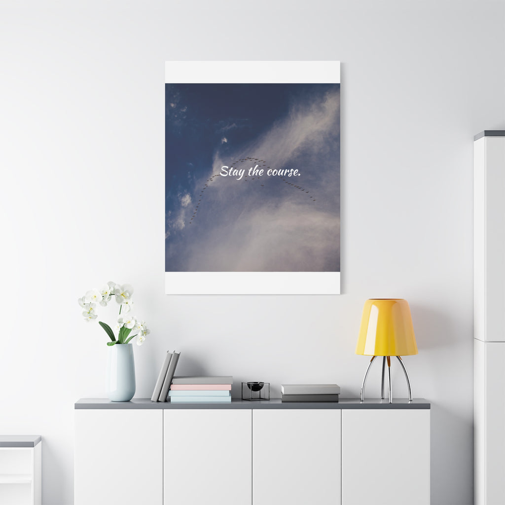 Framed artwork with 'Stay the course.' text on a wall above a white cabinet with decor items.