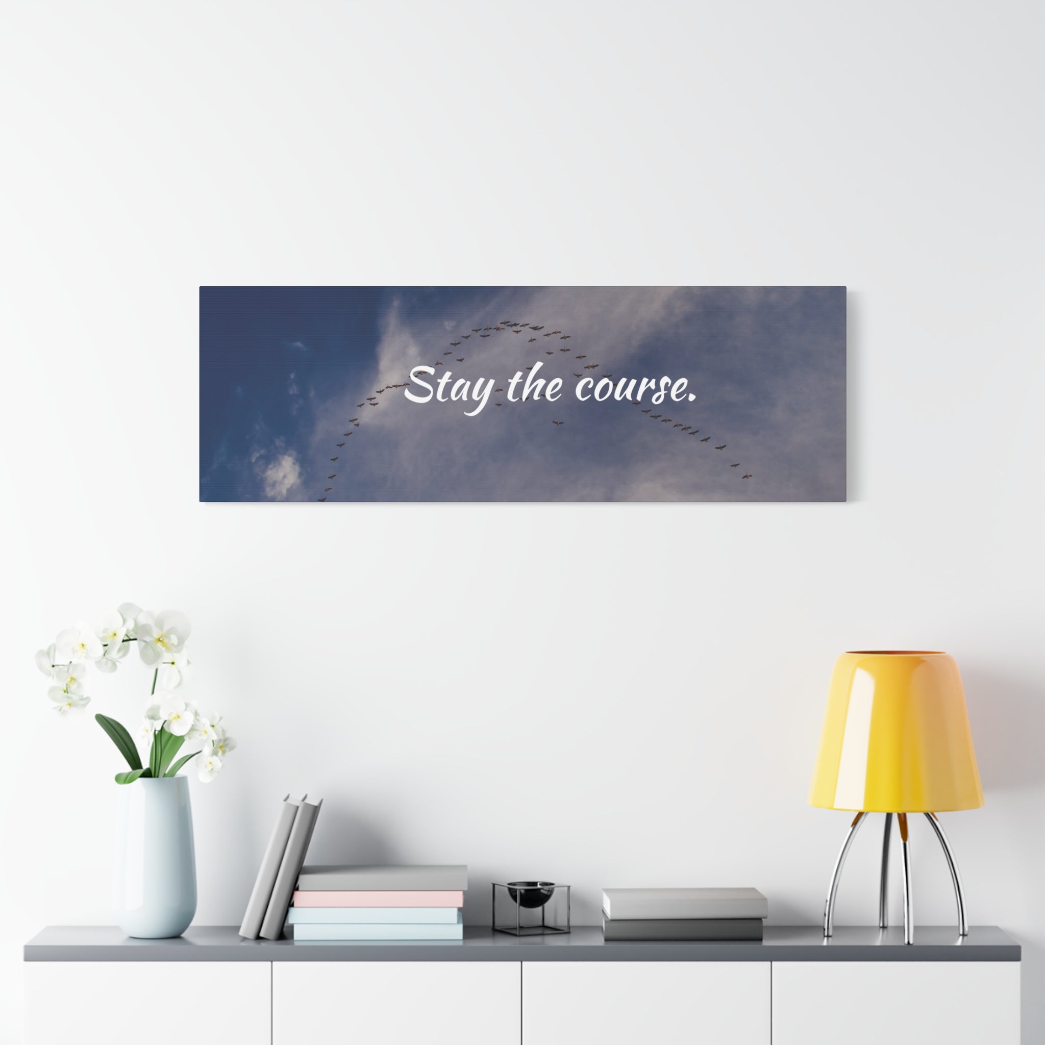 Wall art with 'Stay the course.' text above a shelf with decor items.