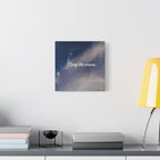 Wall art with 'Stay the course.' text on a celestial background, placed above a desk with books and a lamp.