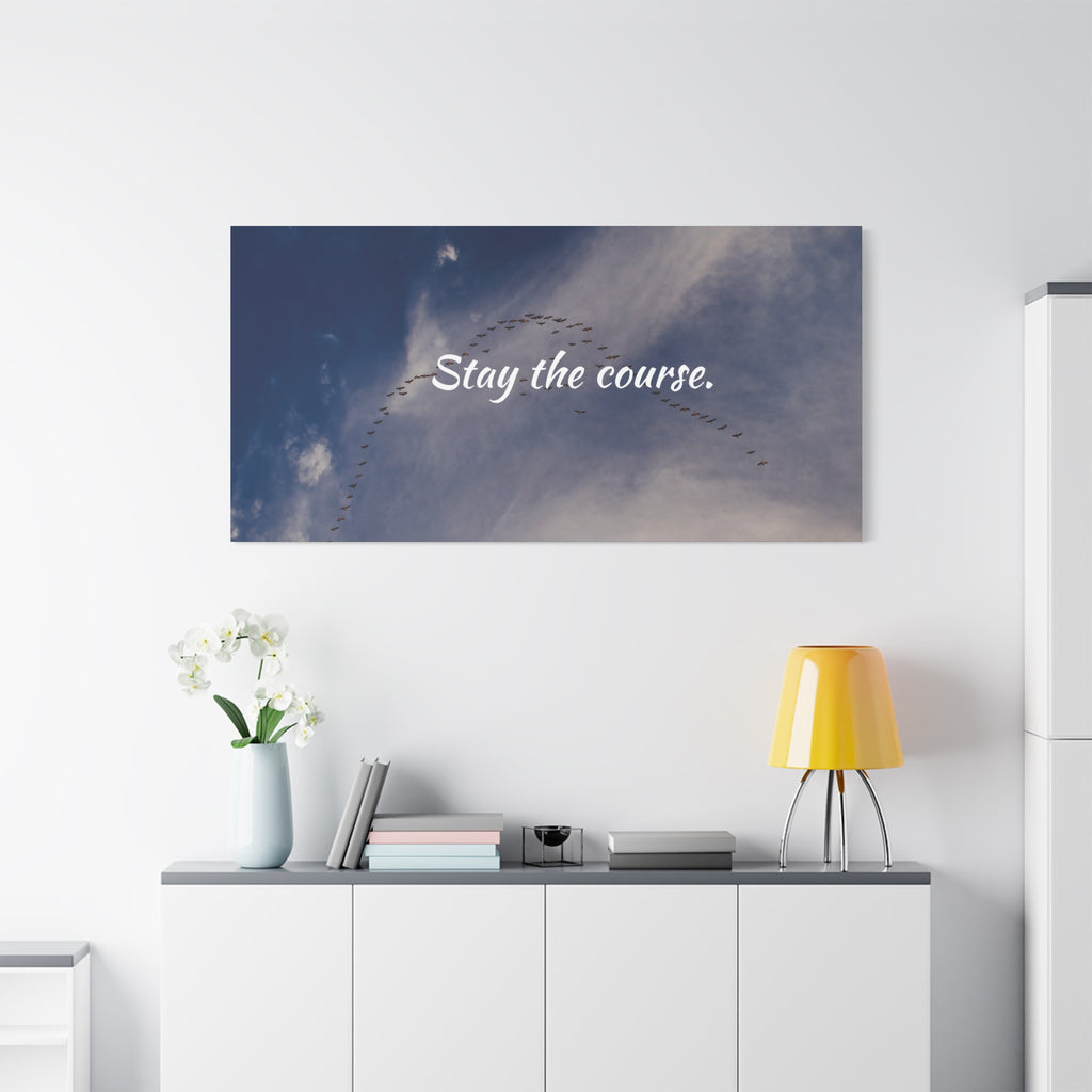 Wall art with 'Stay the course.' text above a white cabinet with decor items.