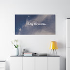 Wall art with 'Stay the course.' text above a white cabinet with decor items.