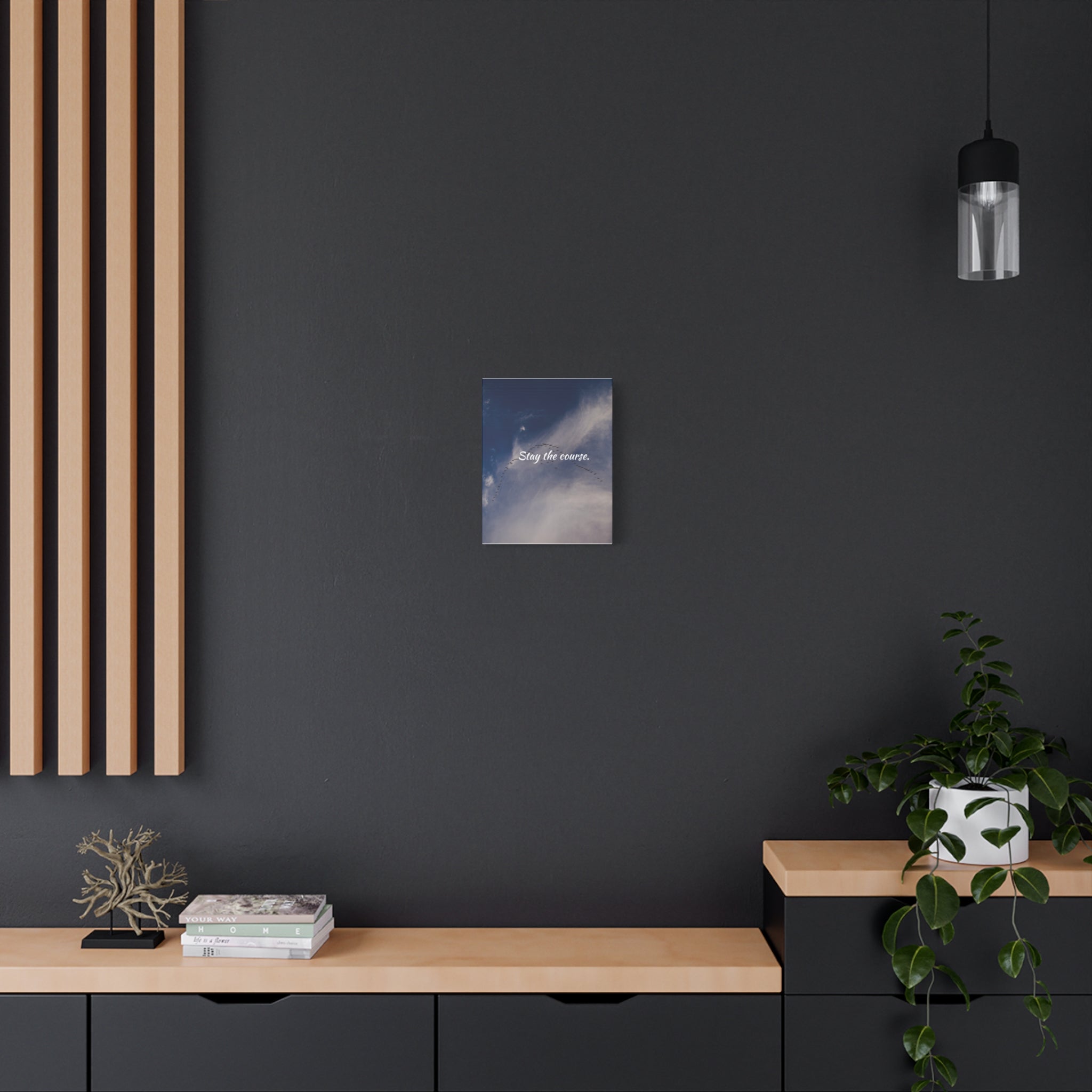 Small square painting on a dark wall above a wooden shelf with decorative items.