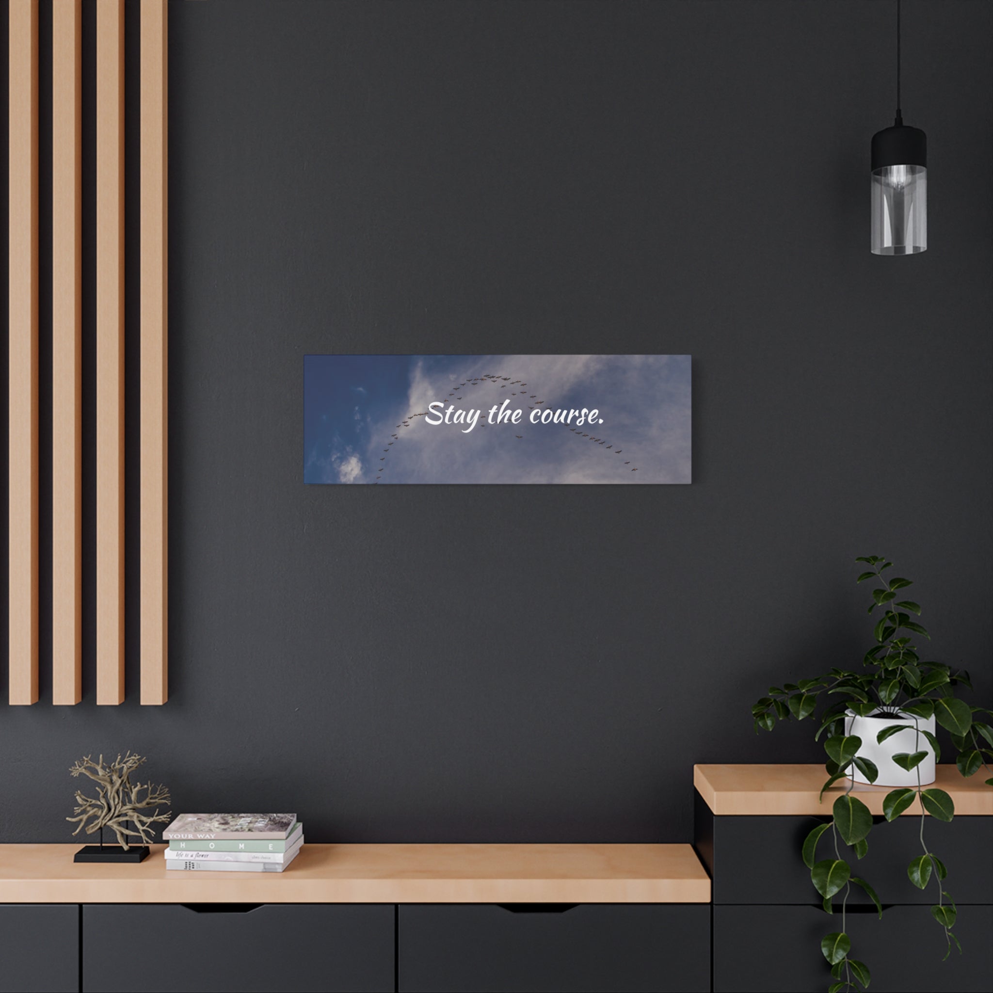 Wall art with 'Stay the course.' text on a dark wall with wooden shelves and decor.
