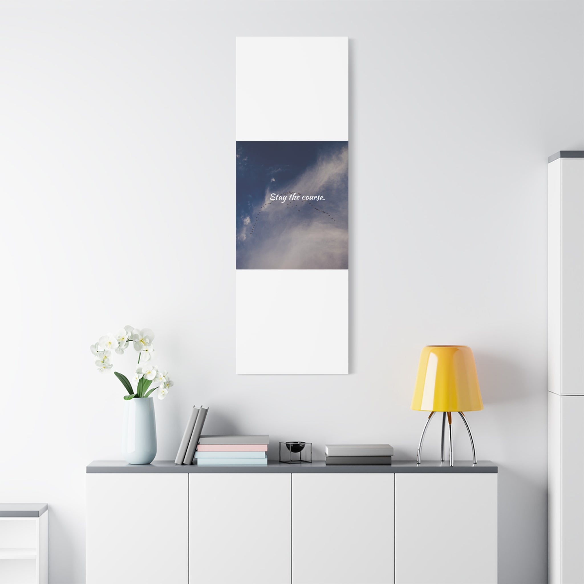 Canvas print with a blue and white abstract design on a wall above a white cabinet.