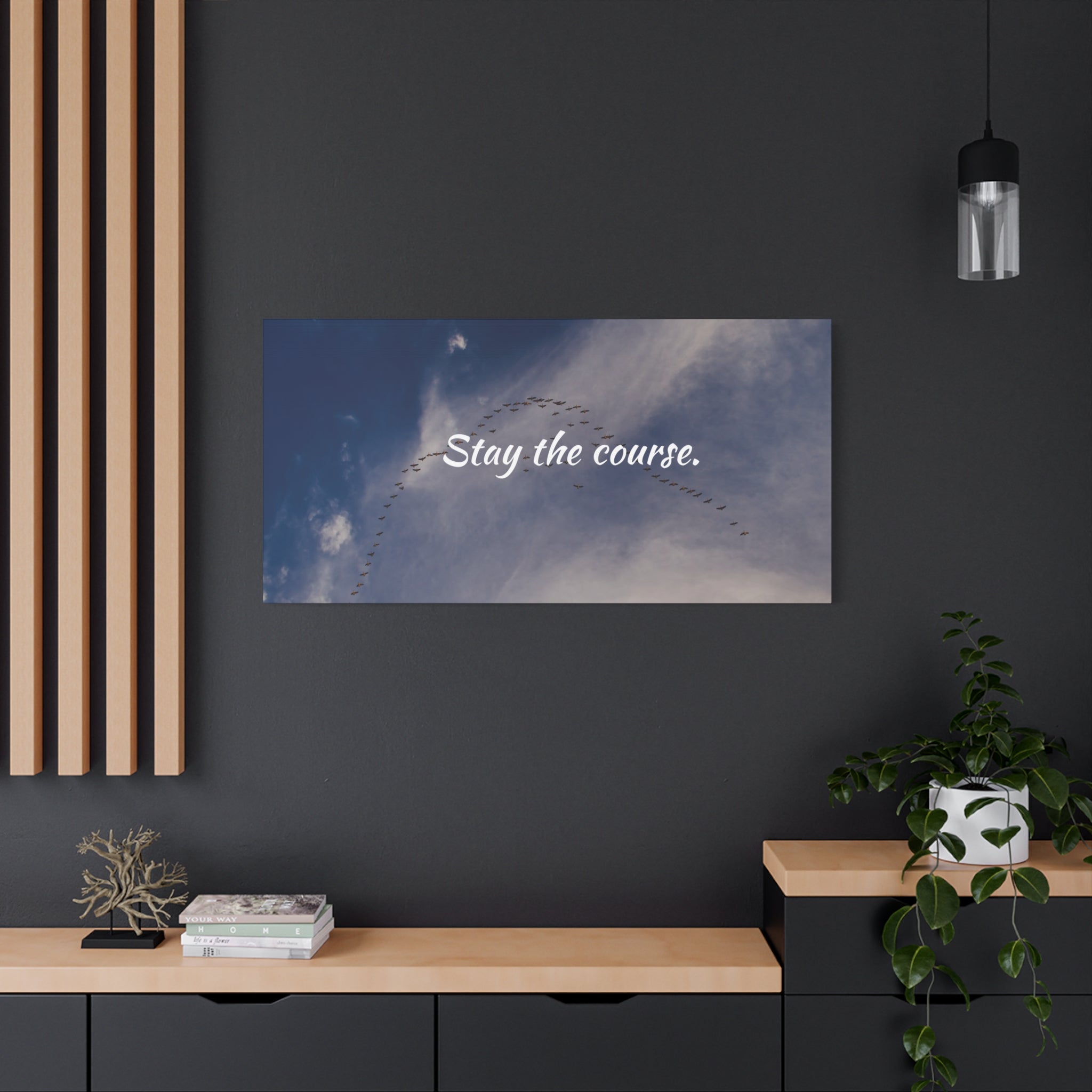 Poster with airplane formation and 'Stay the course.' text on a dark wall above a wooden shelf.