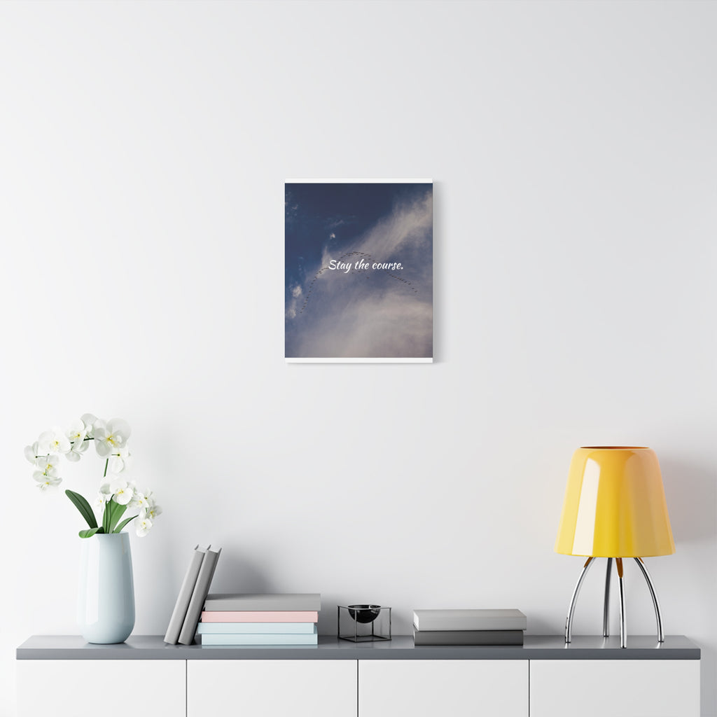 Framed artwork with a celestial design and text on a wall above a shelf with decor items.