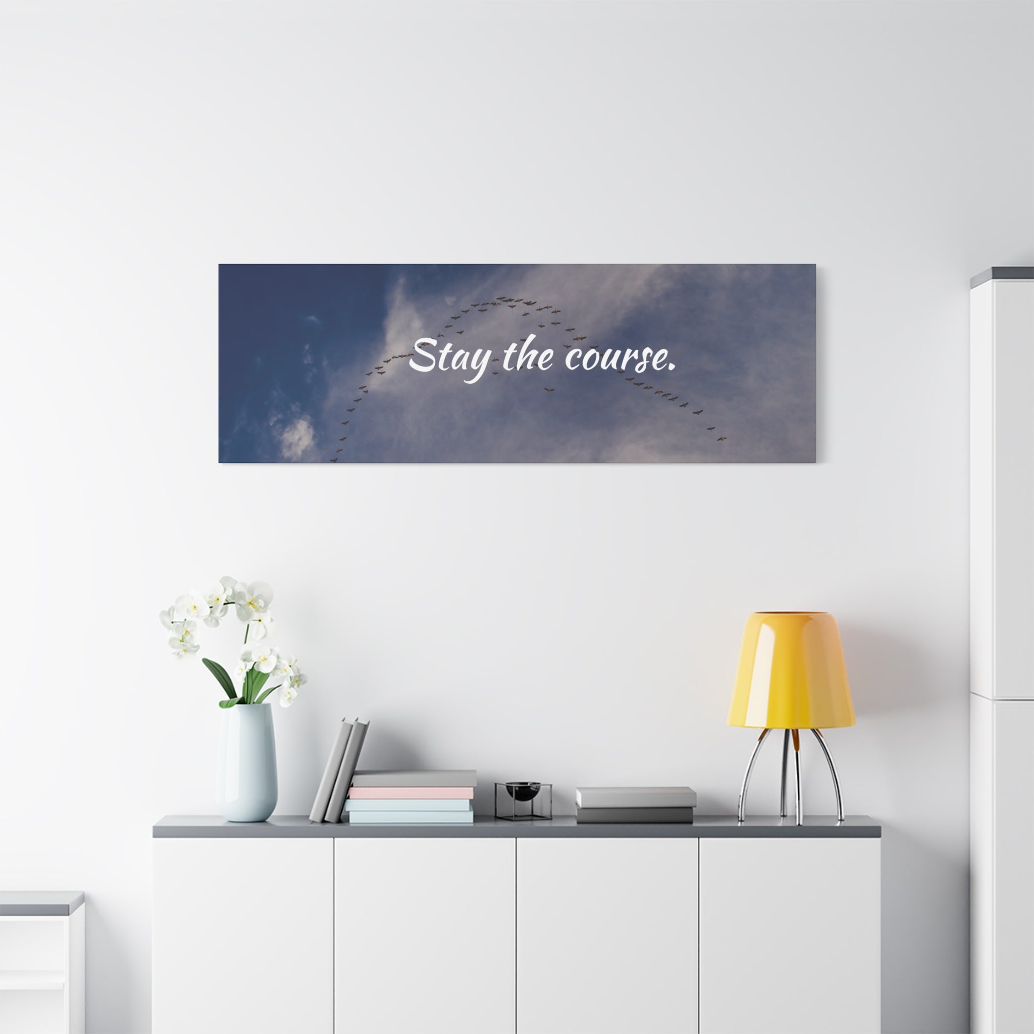 Wall art with 'Stay the course.' text above a desk with decor items.