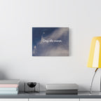 Wall art with 'Stay the course.' text on a blue and white abstract background, placed on a shelf with books and a lamp.