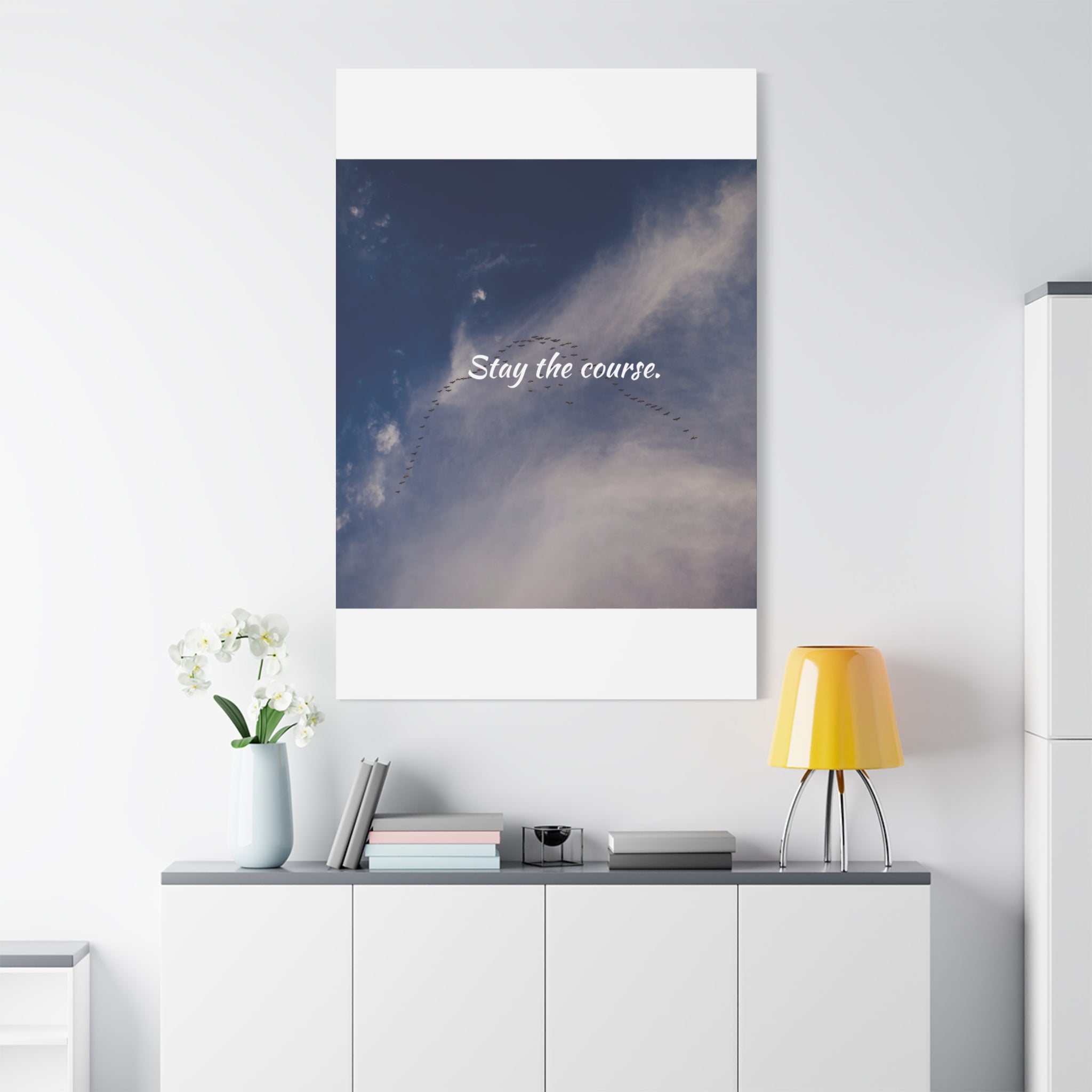 Poster with 'Stay the course.' text on a wall above a desk with decor items.