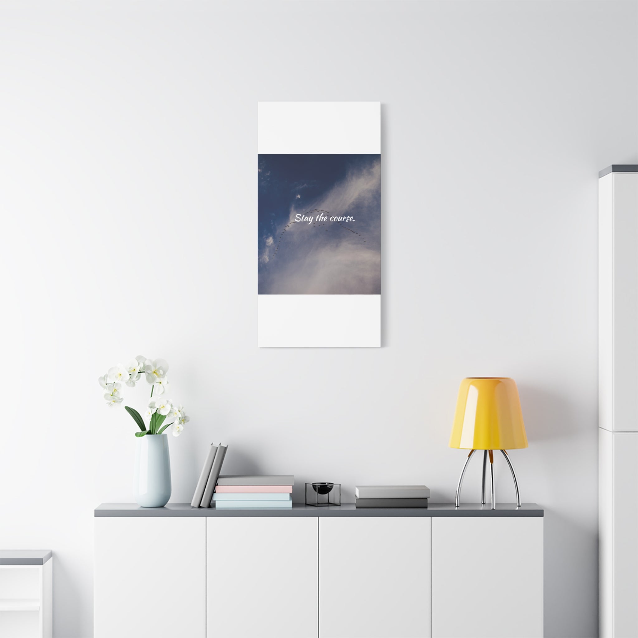 Poster with a cosmic design and text on a white wall above a shelf with decor items.
