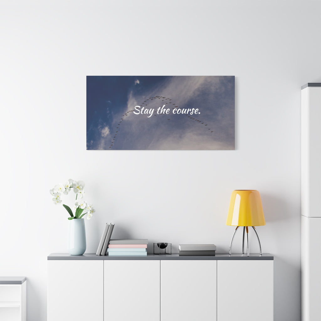 Wall art with 'Stay the course.' text above a white cabinet with decorative items.