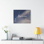 Wall art with 'Stay the course.' text on a blue sky background, displayed above a shelf with decor items.