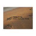 Footprints in sand with motivational quote 'Keep Going. You're closer than you think' on a white background