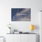 Poster with 'Stay the course.' text on a wall above a white cabinet with decor items.