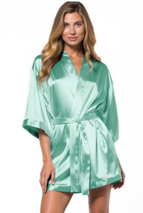 Woman wearing a mint green satin robe on a white background