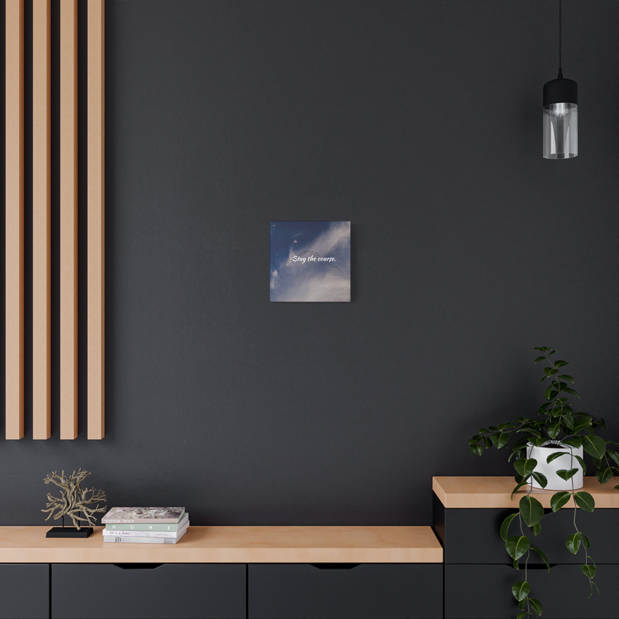 Small square painting on a dark wall above a wooden shelf with decorative items.