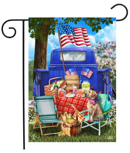 Decorative flag with a picnic scene featuring a blue truck, American flags, and a dog.