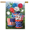 Decorative flag with American flag-themed flower pots and colorful flowers on a grassy background.