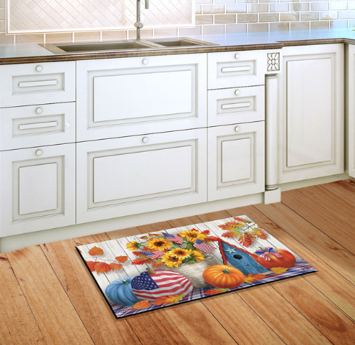 Decorative doormat with autumn design on a wooden floor in a kitchen.