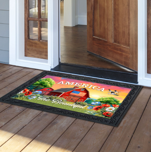 Decorative doormat with a scenic design and 'America the Beautiful' text on a wooden floor.