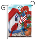 Decorative garden flag with a red birdhouse, cardinal, American flag, and flowers.