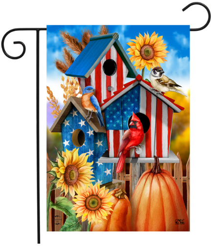 Decorative garden flag with American flag design, birds, sunflowers, and pumpkins on a blue sky background.