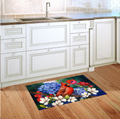 Decorative rug with a floral and cardinal design on a wooden floor in a kitchen.