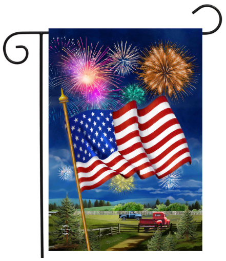 American flag with fireworks against a blue sky, displayed on a flagpole.