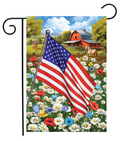American flag on a garden flag with a barn and flowers in the background