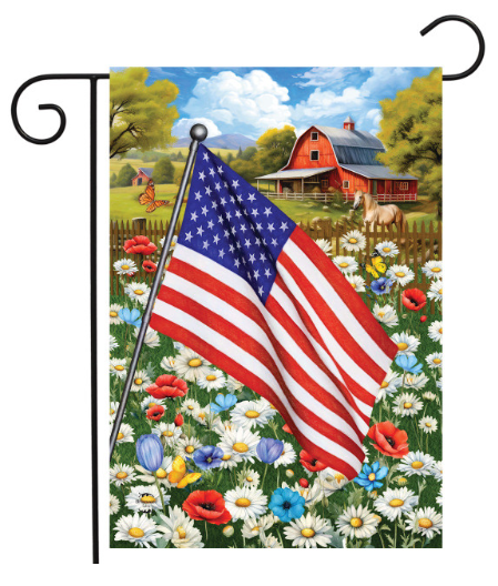 American flag on a garden flag with a barn and flowers in the background