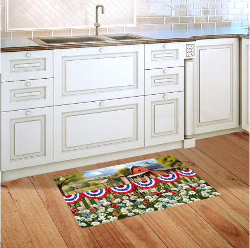 Decorative rug with a barn and floral design on a wooden floor in a kitchen.