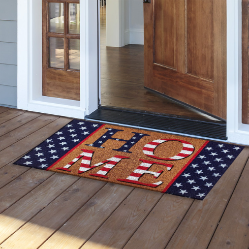 Doormat with 'HOME' text on a wooden floor outside a house.