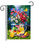 Decorative garden flag with flowers, American flag, watermelon, and lemonade on a grass background.