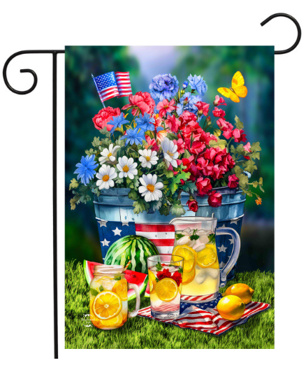 Decorative garden flag with flowers, American flag, watermelon, and lemonade on a grass background.