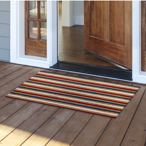 Striped doormat on a wooden floor in front of a house entrance.