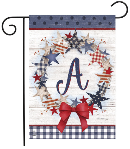 Decorative garden flag with stars, a bow, and the letter 'A' on a wooden background.