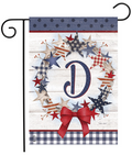 Decorative garden flag with stars, a bow, and the letter 'D' on a wooden background.