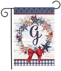 Decorative garden flag with stars, a bow, and the letter 'G' on a wooden background.