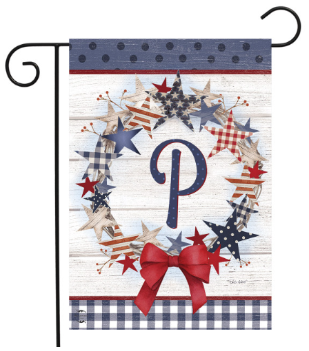 Decorative garden flag with stars, a bow, and a letter 'P' on a wooden background.