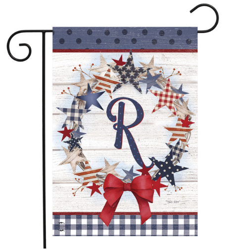 Decorative garden flag with stars, a bow, and the letter 'R' on a wooden background.