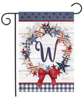 Decorative garden flag with stars, a bow, and the letter 'W' on a wooden background.