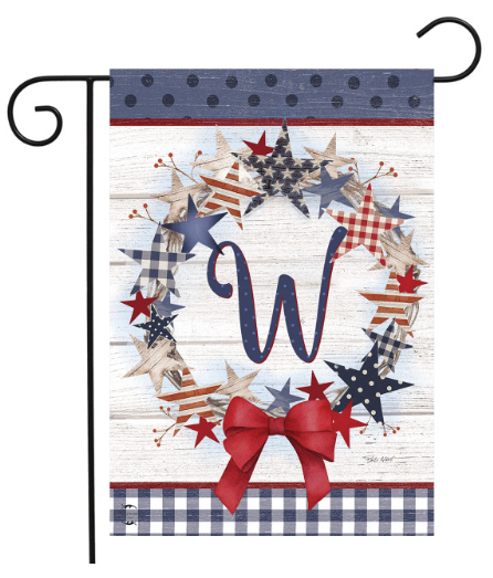 Decorative garden flag with stars, a bow, and the letter 'W' on a wooden background.