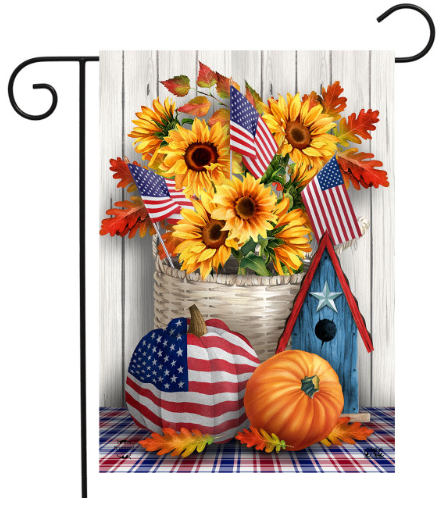 Decorative flag with American flags, sunflowers, pumpkins, and a birdhouse on a wooden background.