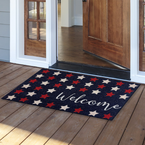 Decorative doormat with star pattern and 'Welcome' text on a wooden floor.