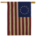 Flag with red and white stripes and blue canton with white stars on a wooden pole.