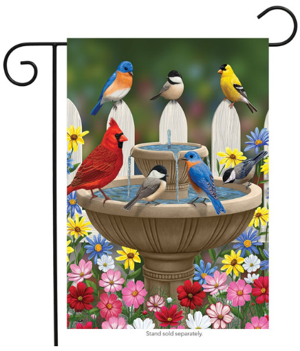 Decorative garden flag with birds around a fountain and colorful flowers.