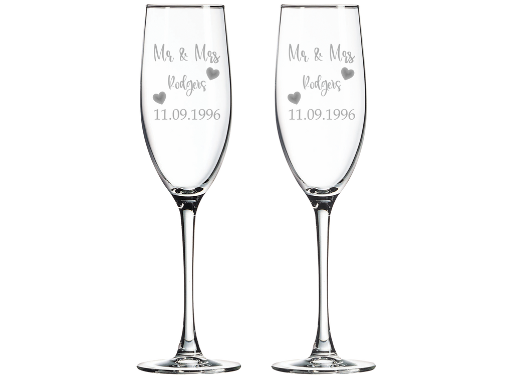 Two champagne flutes with laser engraved 'Mr & Mrs' and personalized text on a white background