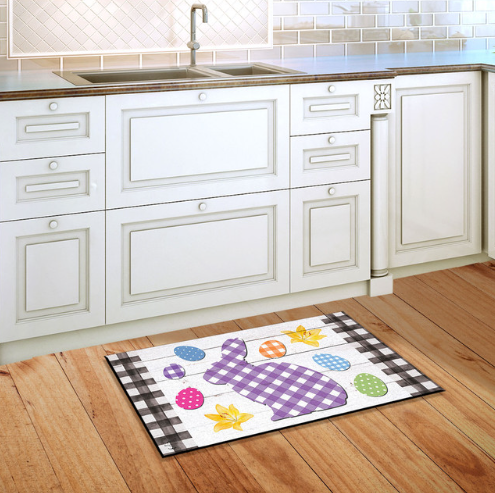Decorative rug with a purple bunny design on a wooden floor in a kitchen.